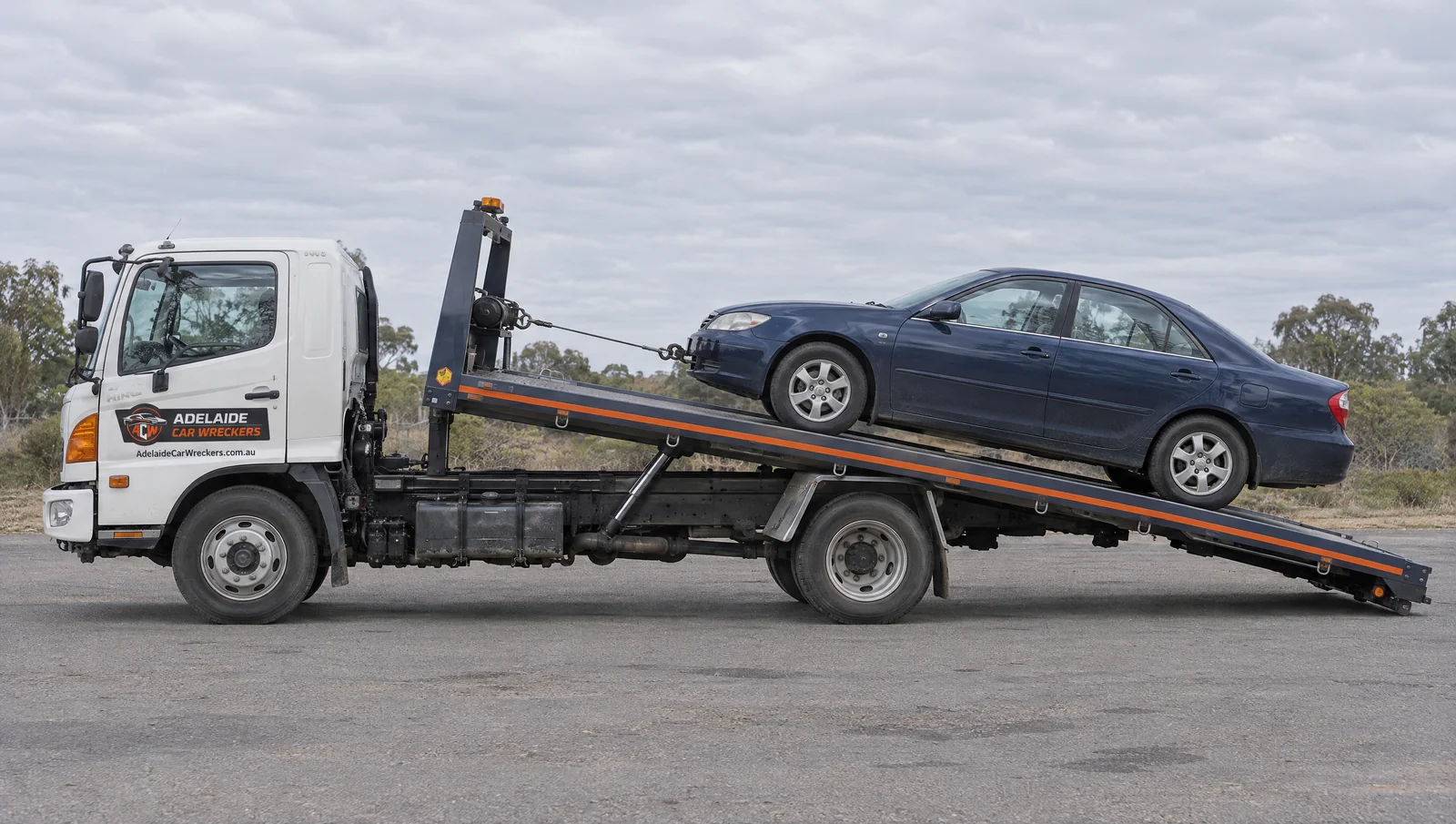 Illustration of a car on a tilted flatbed with Adelaide Car Wreckers branding.