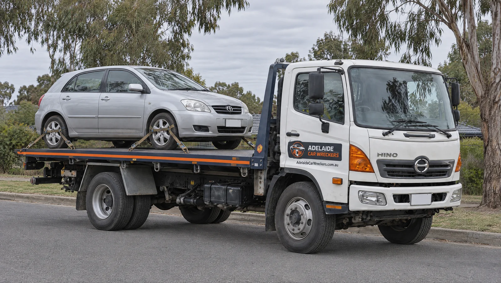 Illustration of a car secured on a flatbed truck with Adelaide Car Wreckers branding.